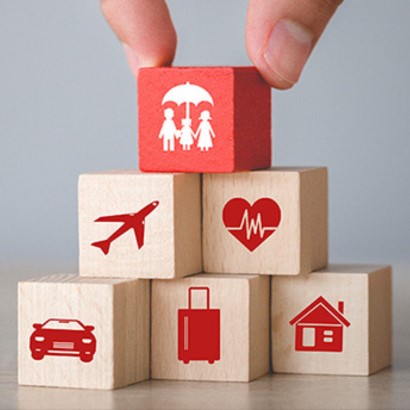 Шест кубчета едно върху друго, на които има картинки на семейство с чадър, самолет, кола, сърце, куфар и къща.